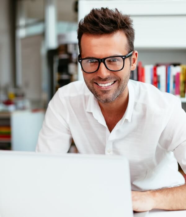 Lachende man met bril werkt op laptop