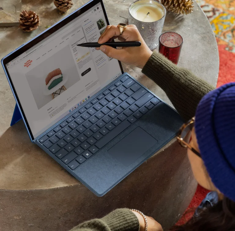 Persoon die een blauwe Microsoft Surface Pro 7+ met stylus gebruikt en op een website surft.