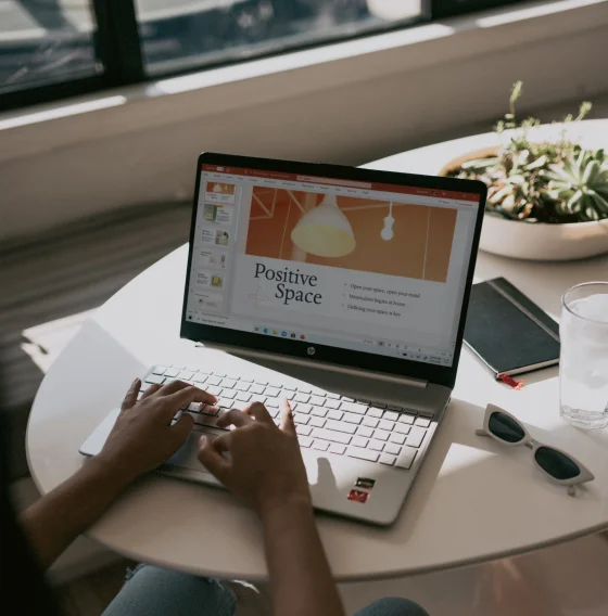 Persoon die op een laptop werkt en de presentatie 'Positive Space' toont.