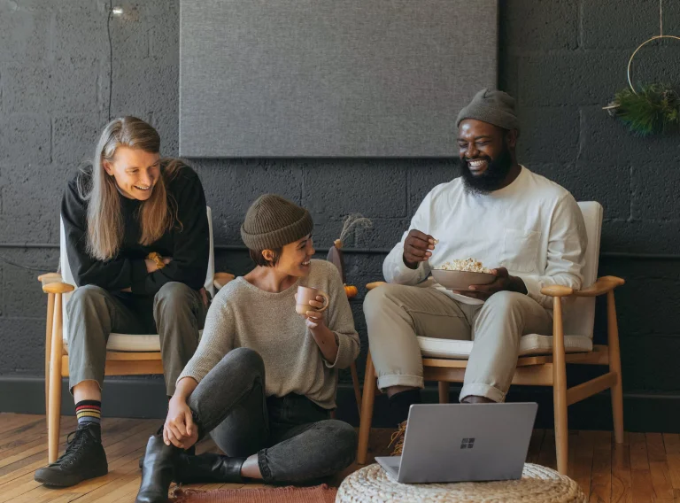 Drie vrienden genieten van een filmavondje en delen popcorn en drankjes.