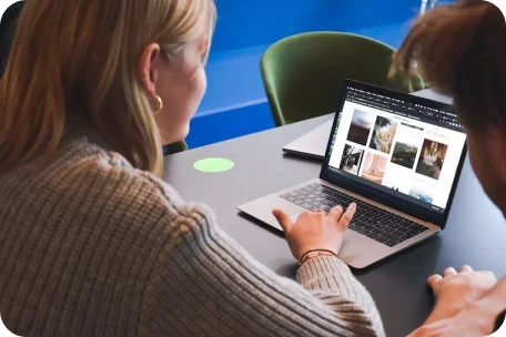 Twee mensen werken samen op een laptop en bekijken afbeeldingen voor een project.